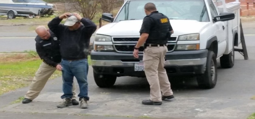 photo of officers patting down a suspect caught working without a license